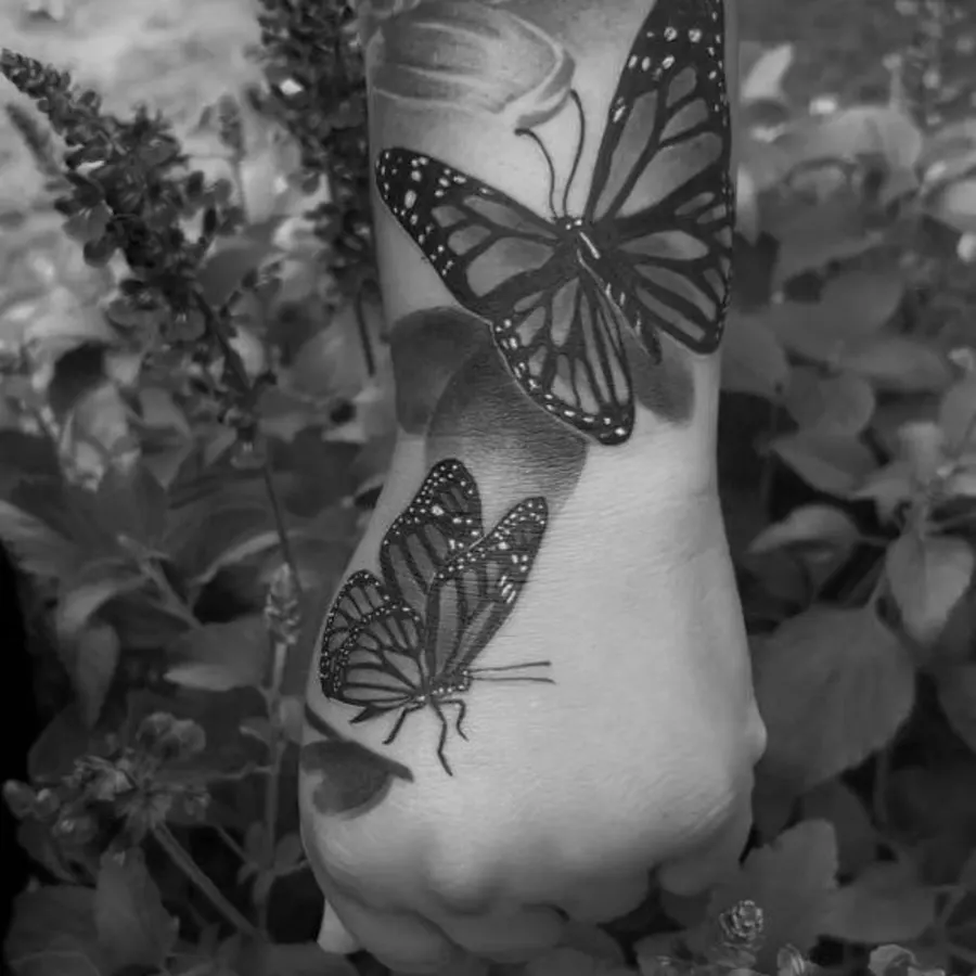 Realistic monarch butterfly tattoo on hand in black and grey